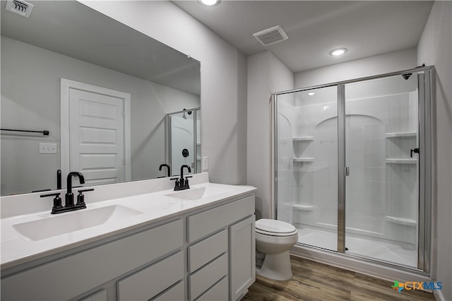 bathroom with toilet, vanity, hardwood / wood-style flooring, and a shower with shower door