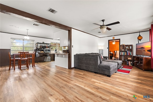 living room featuring ceiling fan, light hardwood / wood-style floors, and beamed ceiling