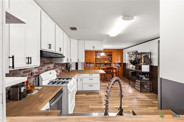 kitchen with wooden counters, light wood-type flooring, white gas range, and white cabinetry