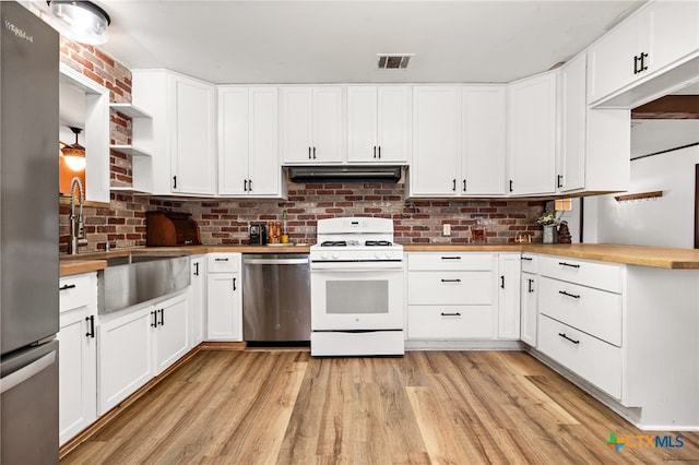 kitchen featuring wooden counters, light wood-type flooring, stainless steel appliances, and white cabinetry