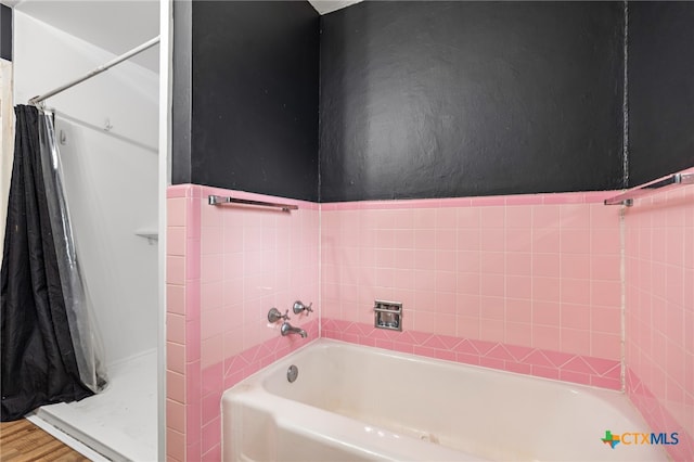 bathroom featuring wood-type flooring, separate shower and tub, and tile walls