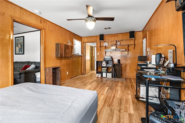 bedroom featuring light hardwood / wood-style floors, wood walls, and ceiling fan