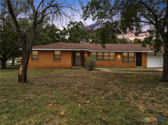 single story home featuring a garage and a yard