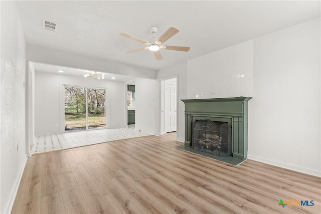 unfurnished living room with ceiling fan with notable chandelier and light hardwood / wood-style floors