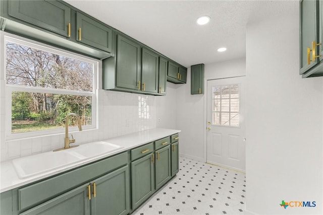 kitchen with tasteful backsplash, sink, green cabinets, and a textured ceiling