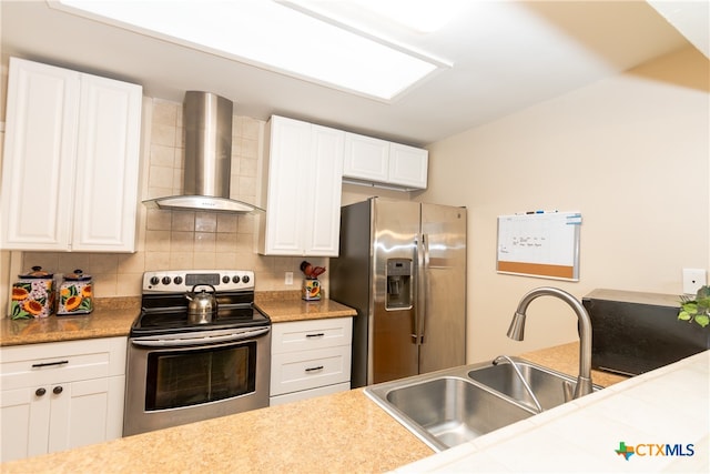 kitchen featuring wall chimney exhaust hood, sink, tasteful backsplash, white cabinetry, and appliances with stainless steel finishes