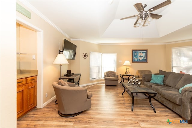 living room featuring ornamental molding, light wood-type flooring, a tray ceiling, and ceiling fan