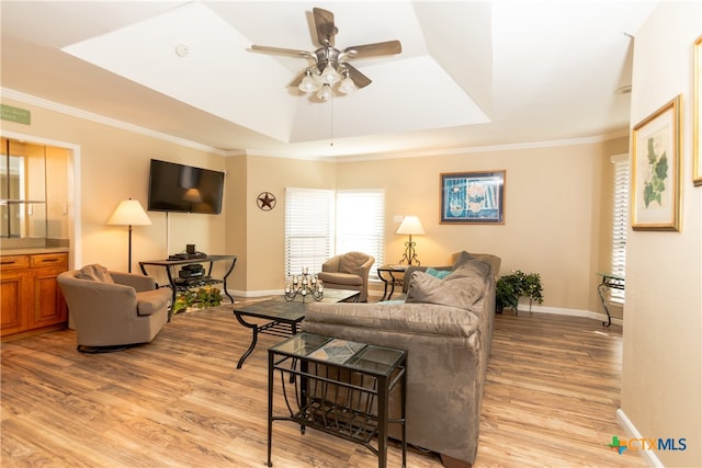 living room featuring light hardwood / wood-style floors, ceiling fan, crown molding, and a tray ceiling