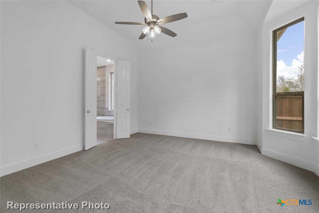 empty room featuring ceiling fan, carpet floors, and vaulted ceiling