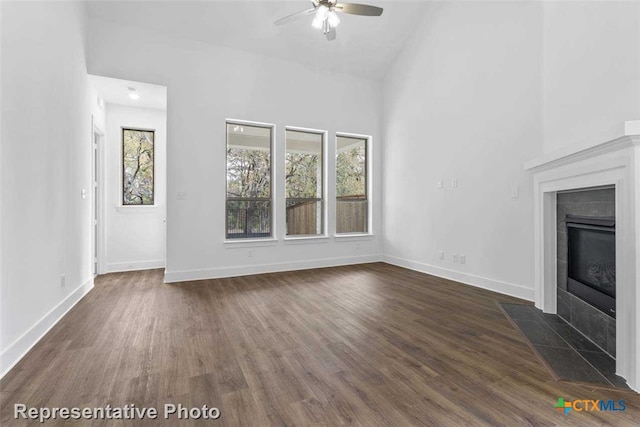 unfurnished living room with ceiling fan, a fireplace, and dark wood-type flooring