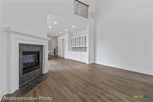 unfurnished living room with dark wood-type flooring and a tile fireplace