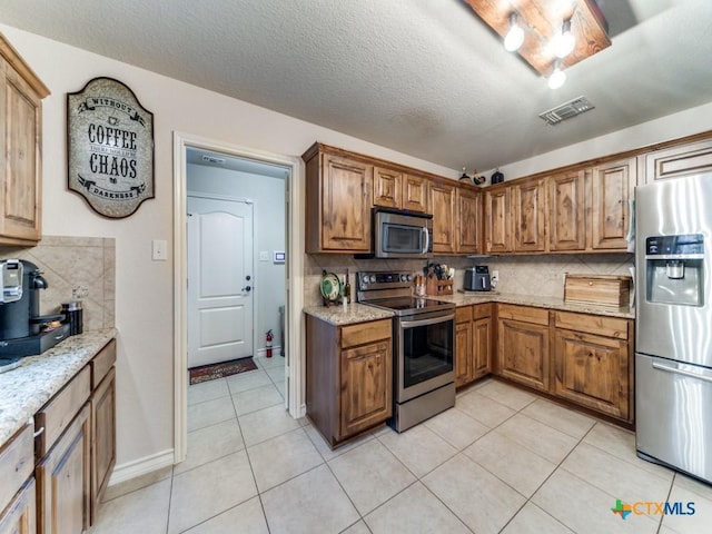 1777 Crossbow Dr, Canyon Lake, TX 78133 - kitchen featuring brown cabinets, stainless steel appliances, visible vents, and tasteful backsplash