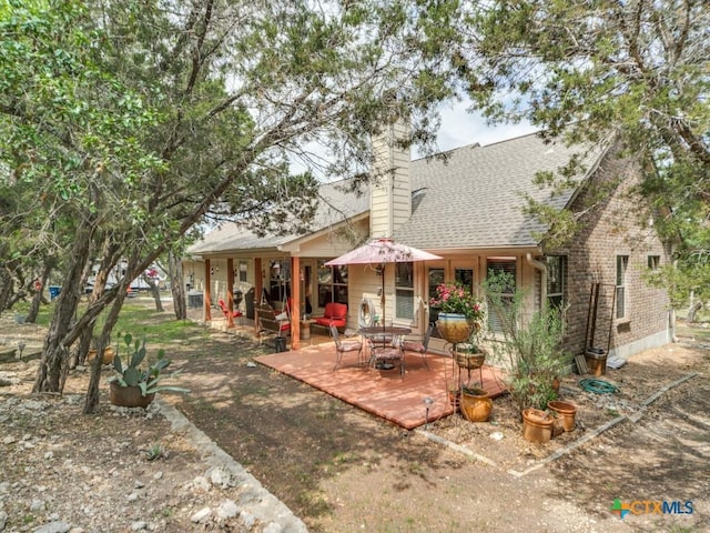 1777 Crossbow Dr, Canyon Lake, TX 78133 - rear view of property featuring a patio, a shingled roof, and a chimney