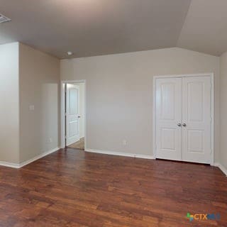 5120 Siltstone Loop, Killeen, TX 76542 - unfurnished bedroom with wood finished floors, baseboards, and lofted ceiling