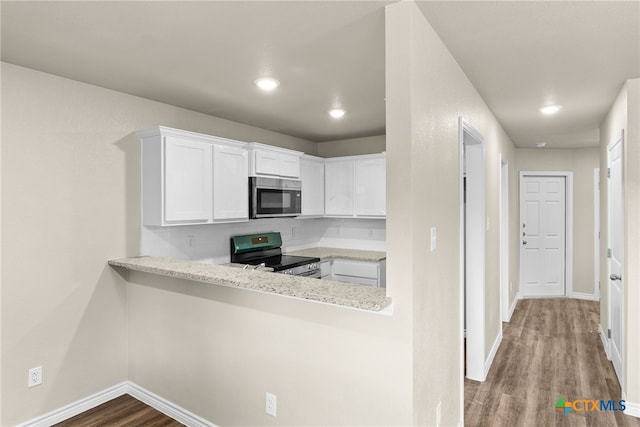 kitchen featuring stainless steel appliances, kitchen peninsula, hardwood / wood-style flooring, light stone countertops, and white cabinetry