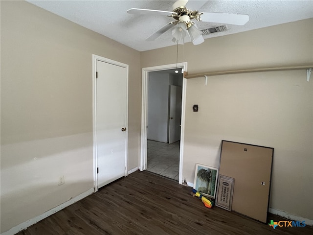 unfurnished room with ceiling fan, wood finished floors, visible vents, and baseboards