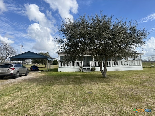 view of yard with dirt driveway, a porch, and a detached carport