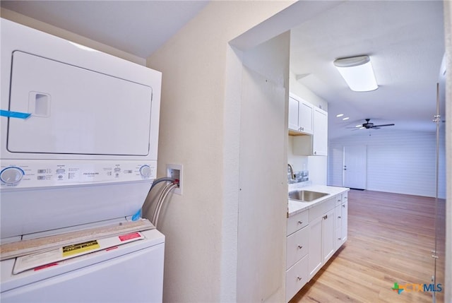 washroom with light hardwood / wood-style floors, ceiling fan, stacked washer / drying machine, and sink