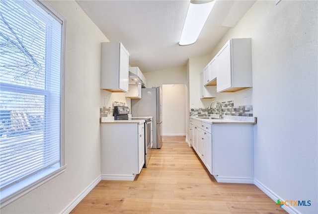 kitchen with sink, light hardwood / wood-style flooring, stainless steel electric stove, decorative backsplash, and white cabinets