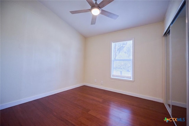 unfurnished bedroom with ceiling fan, a closet, dark wood-type flooring, and vaulted ceiling