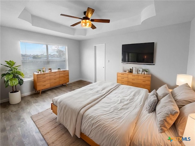 bedroom featuring a tray ceiling, ceiling fan, and light hardwood / wood-style floors