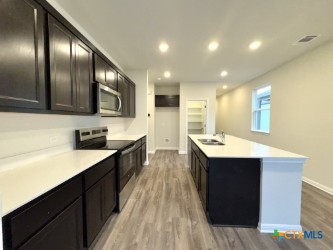 kitchen featuring appliances with stainless steel finishes, sink, a kitchen island with sink, and light hardwood / wood-style floors