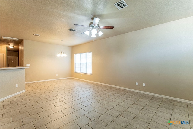 tiled empty room featuring ceiling fan with notable chandelier and a textured ceiling