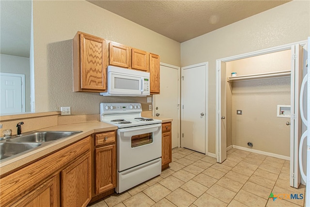 kitchen featuring sink, white appliances, and a textured ceiling