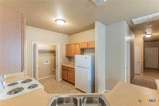 kitchen with sink, white appliances, and a textured ceiling