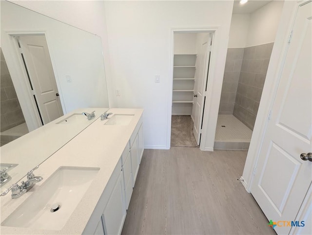 813 Bobby Lou Ln, Copperas Cove, TX 76522 - bathroom featuring wood finished floors, double vanity, a tile shower, and baseboards