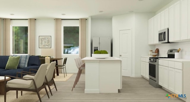 kitchen featuring a kitchen island with sink, white cabinetry, stainless steel appliances, a wealth of natural light, and light wood-type flooring