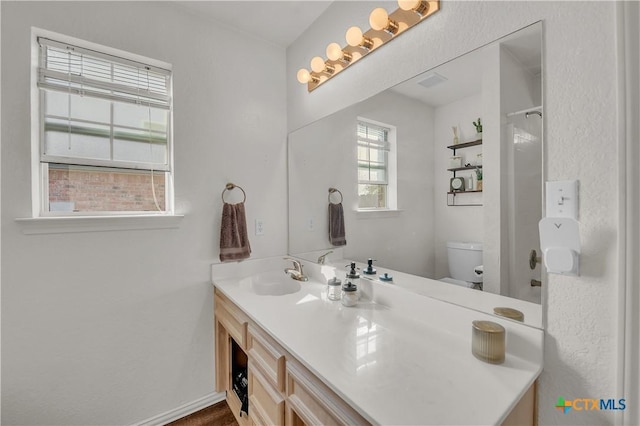 bathroom featuring walk in shower, vanity, and toilet