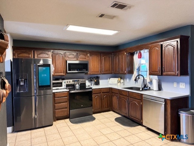 kitchen with a sink, visible vents, appliances with stainless steel finishes, and light countertops