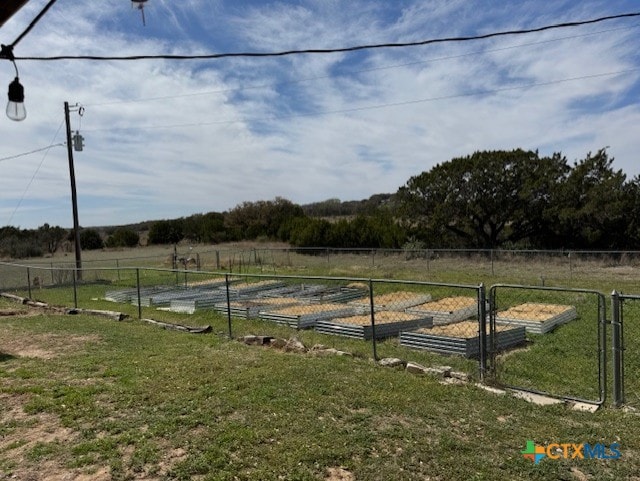 view of yard with a gate, a garden, a rural view, and fence