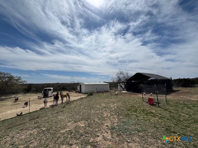 view of yard featuring an outdoor structure, a rural view, and a pole building