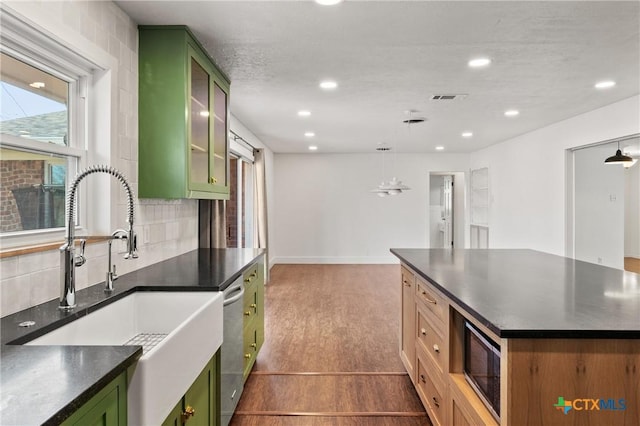 kitchen featuring appliances with stainless steel finishes, dark countertops, a sink, and green cabinets