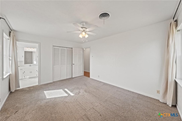 unfurnished bedroom with a closet, carpet flooring, visible vents, and connected bathroom