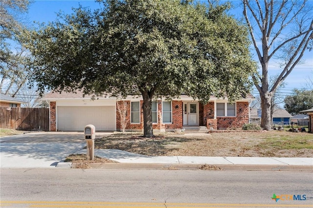 view of front of house featuring an attached garage, fence, concrete driveway, and brick siding