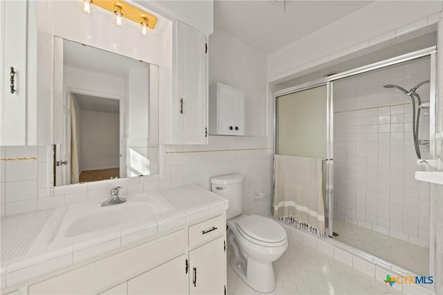 full bath featuring toilet, tile patterned floors, vanity, a shower stall, and tile walls