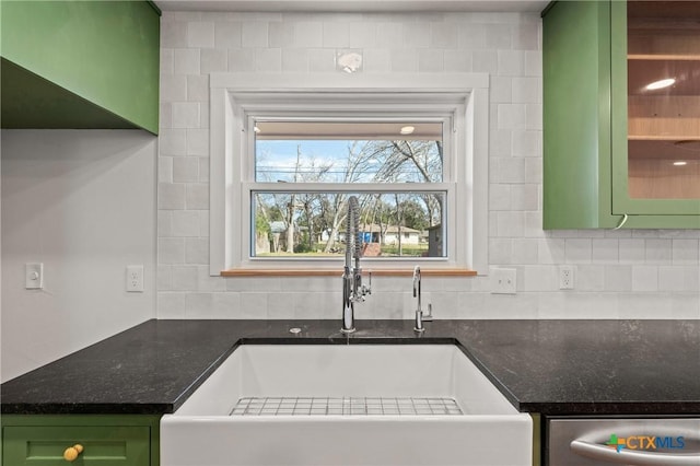 kitchen featuring dishwasher, dark stone counters, green cabinets, and a sink