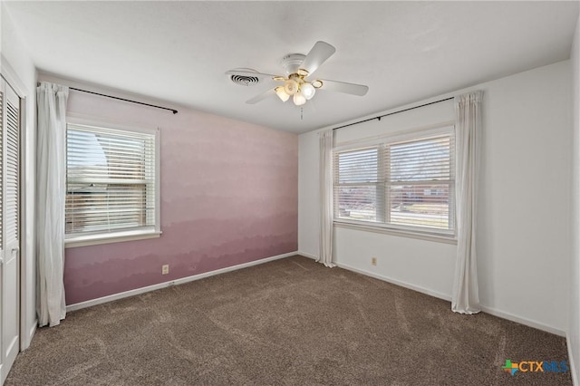 carpeted empty room featuring visible vents, ceiling fan, and baseboards