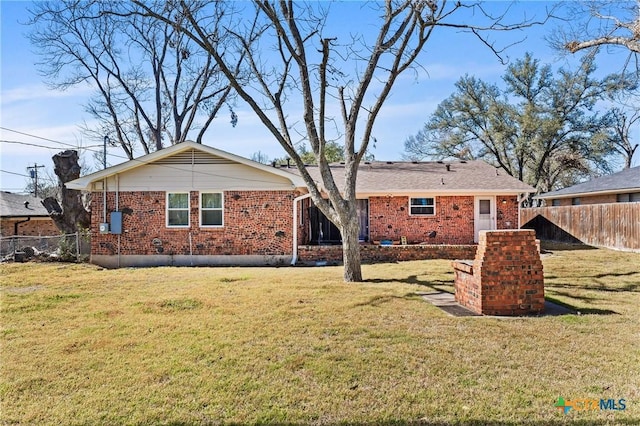 back of property with fence, a lawn, and brick siding