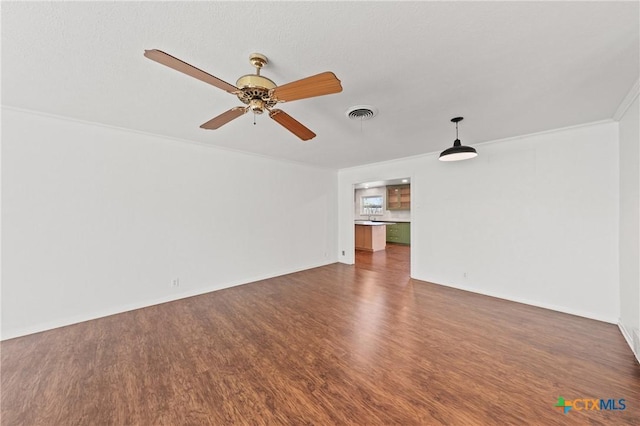 spare room featuring crown molding, visible vents, ceiling fan, wood finished floors, and baseboards