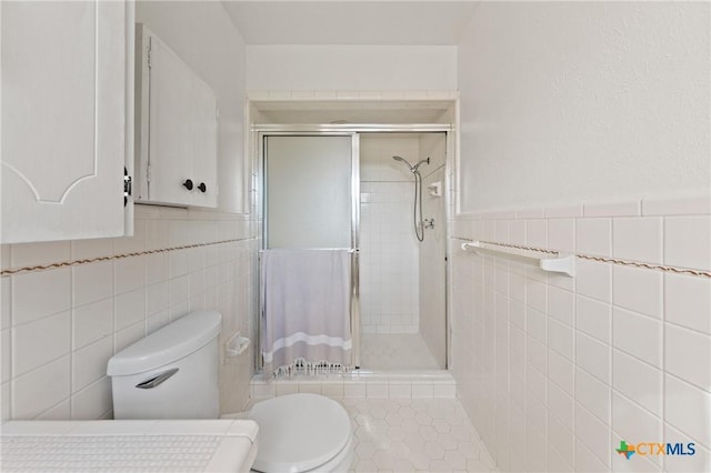 full bathroom featuring toilet, a wainscoted wall, a shower stall, and tile walls