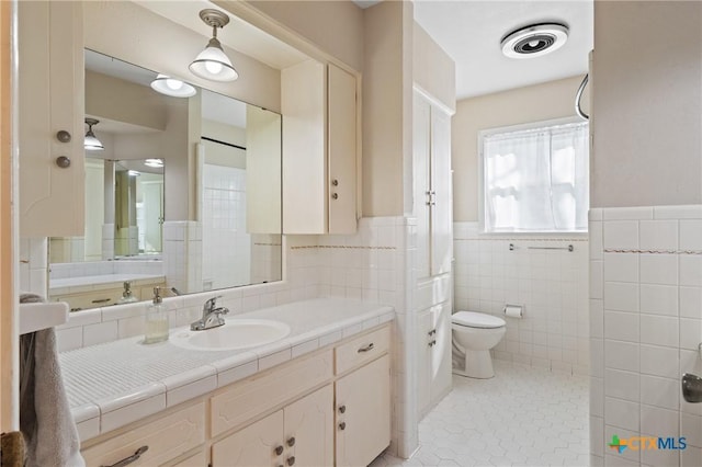 bathroom featuring tile patterned flooring, toilet, visible vents, tile walls, and wainscoting