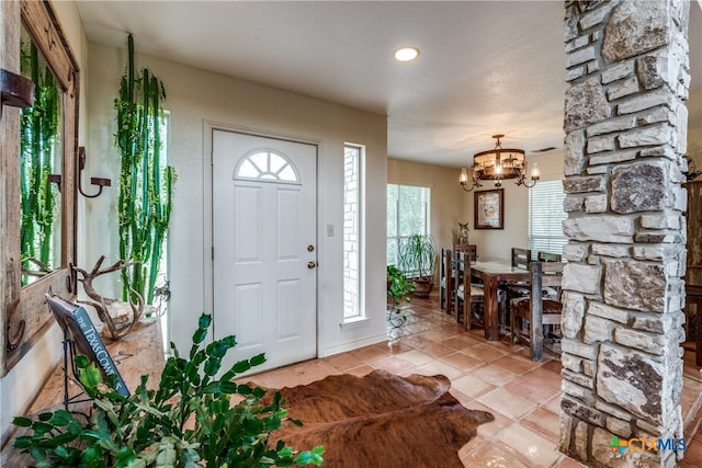 tiled foyer entrance featuring a chandelier, a textured ceiling, and a healthy amount of sunlight