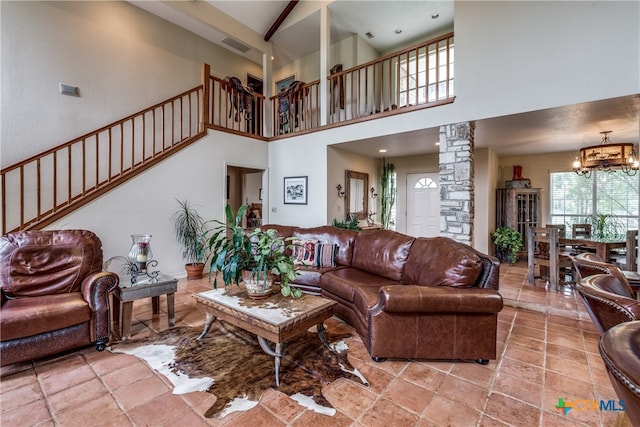 living room with a high ceiling, decorative columns, and a chandelier