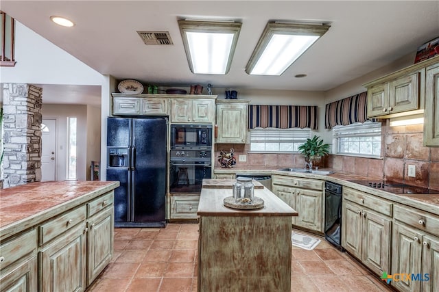 kitchen with black appliances, ornate columns, sink, decorative backsplash, and a center island