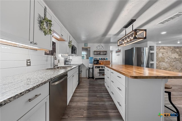 kitchen with sink, a kitchen island, butcher block countertops, white cabinets, and appliances with stainless steel finishes