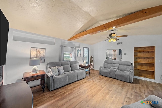 living room with light wood-type flooring, a textured ceiling, vaulted ceiling with beams, and ceiling fan